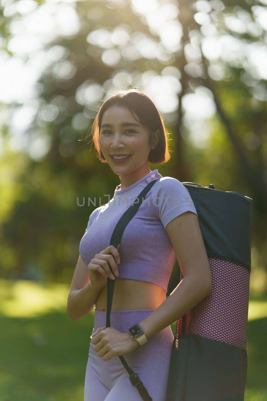 Attractive Asian female in sportswear practicing yoga in the outdoor park.