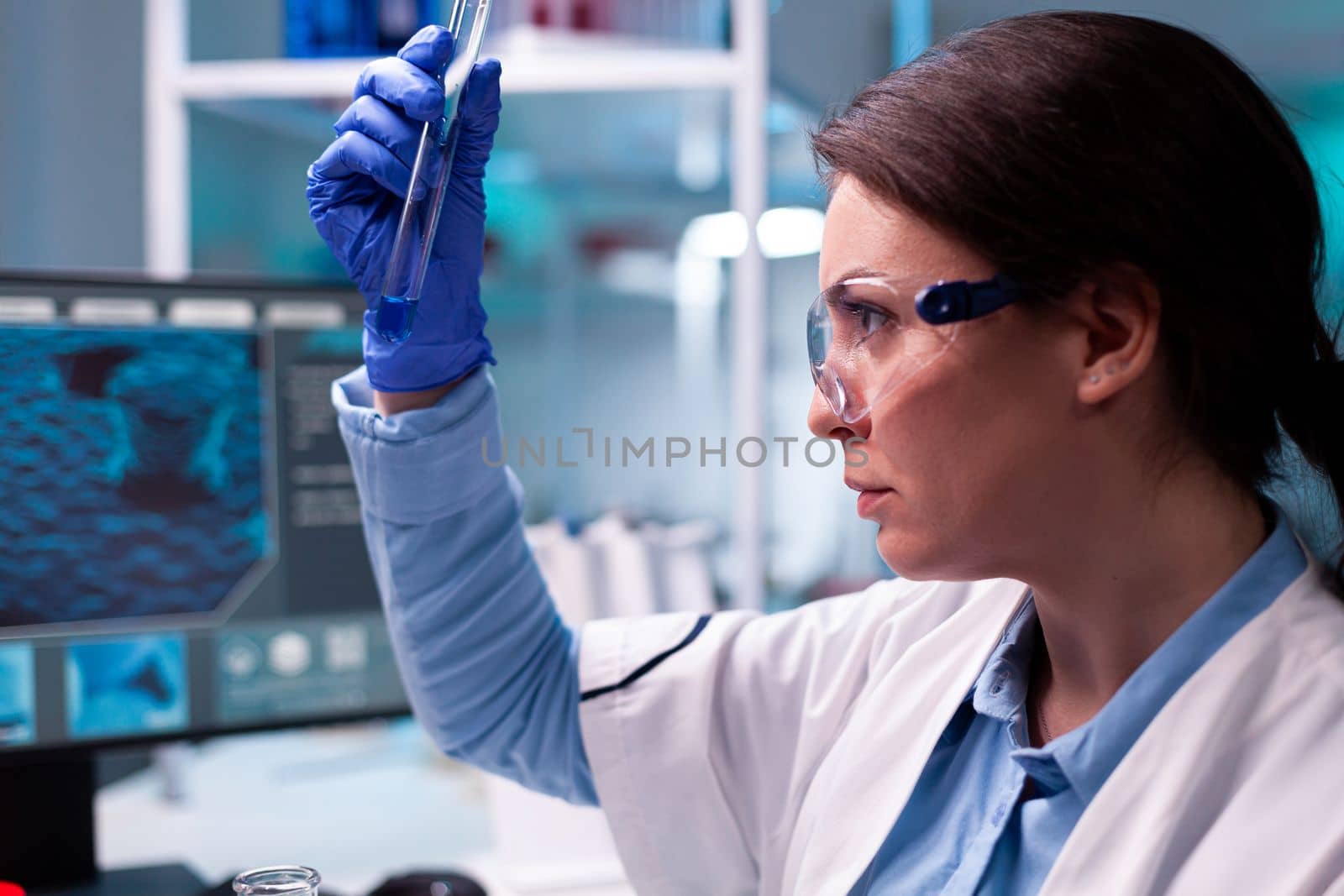 Close up of scinetist analyzing liquid medical test tube in scientific lab. Pharmaceutical biotechnologist in research laboratory works with test tube to find vaccine glove.