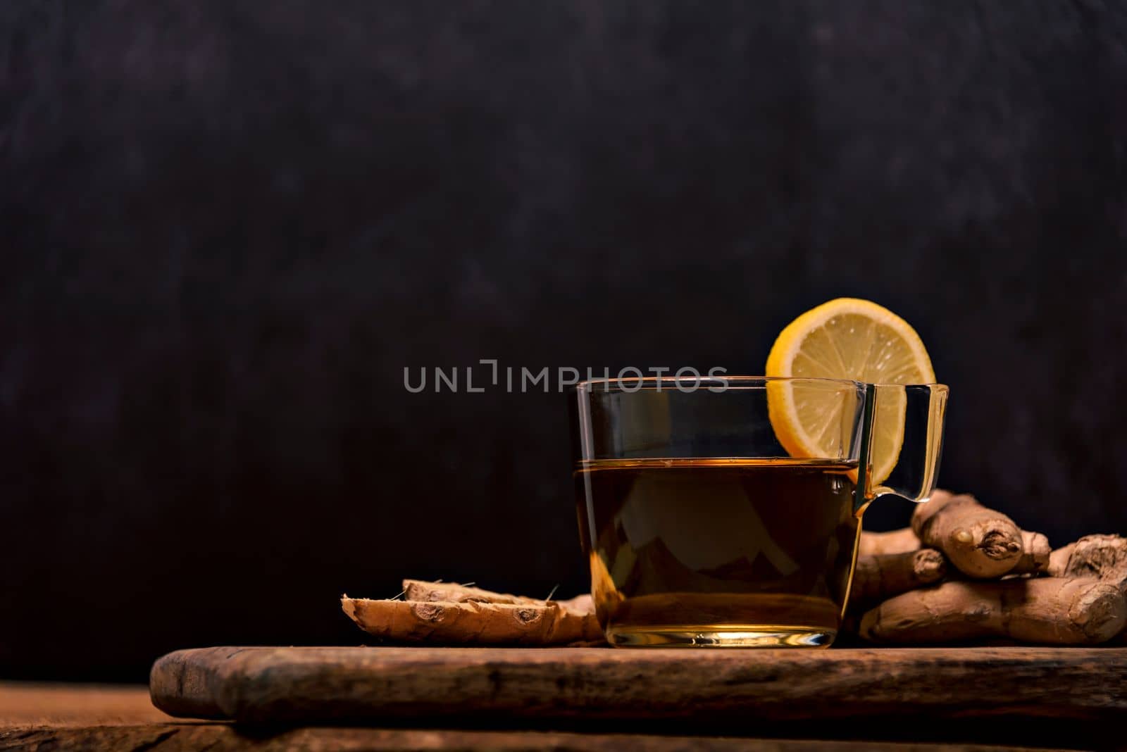 Cup of spiced tea with cinnamon sticks, anise star, lemon and jinger on rustic table