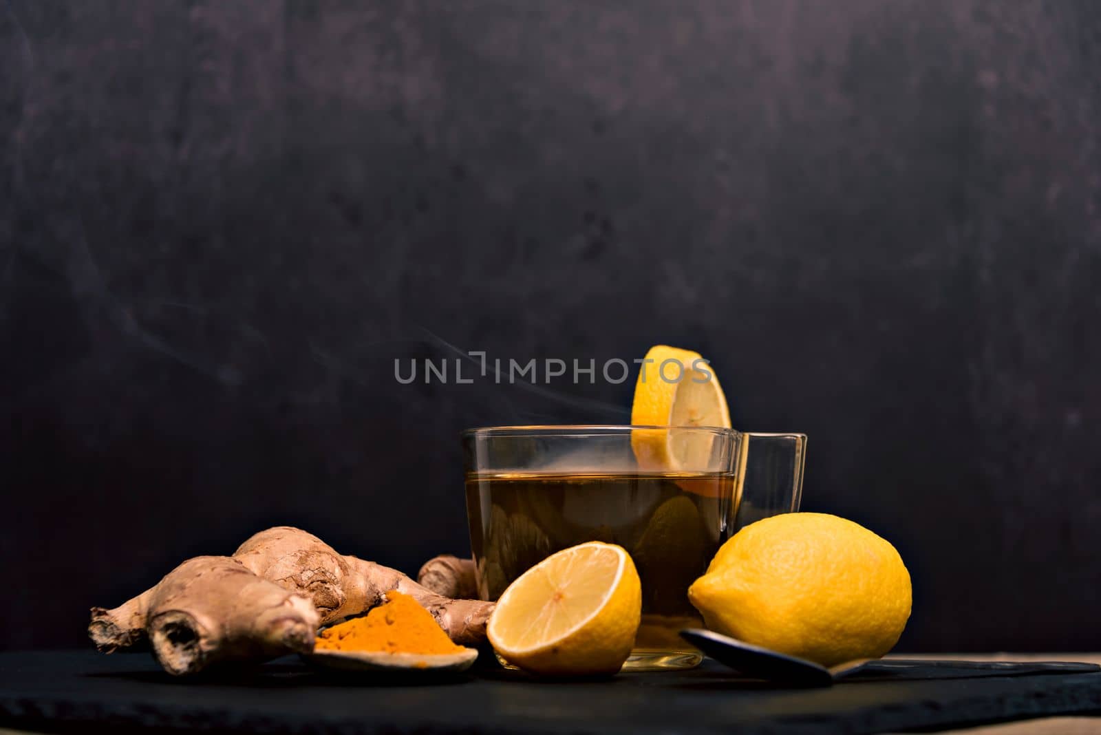 Cup of spiced tea with cinnamon sticks, anise star, lemon and jinger on rustic table