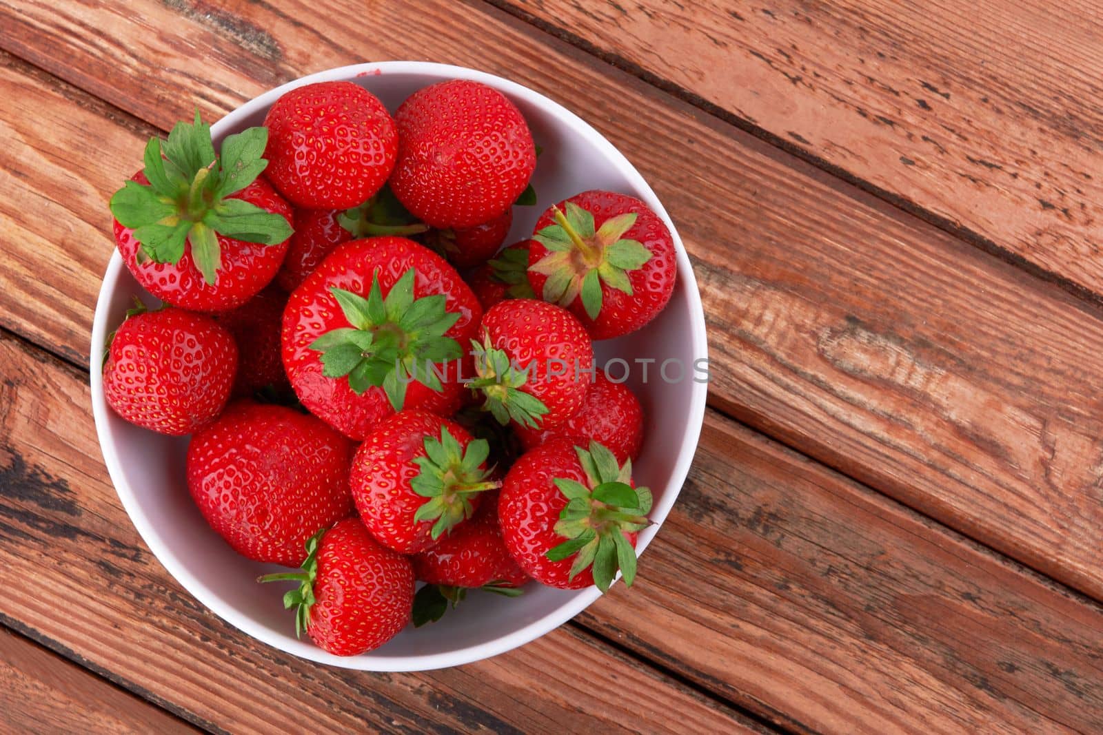 Strawberries in a saucer on a wooden background