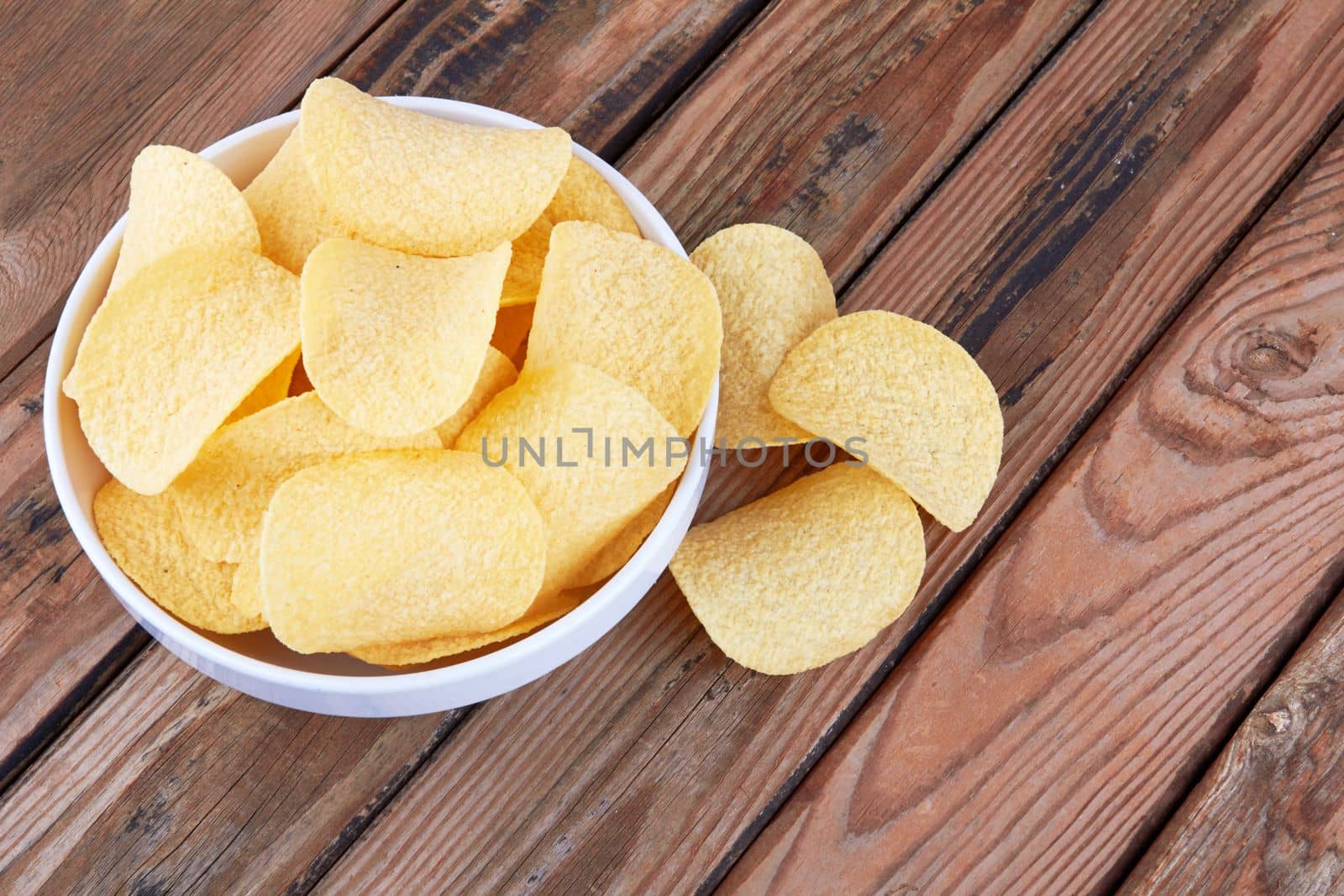 Potato chips on a wooden surface in a saucer