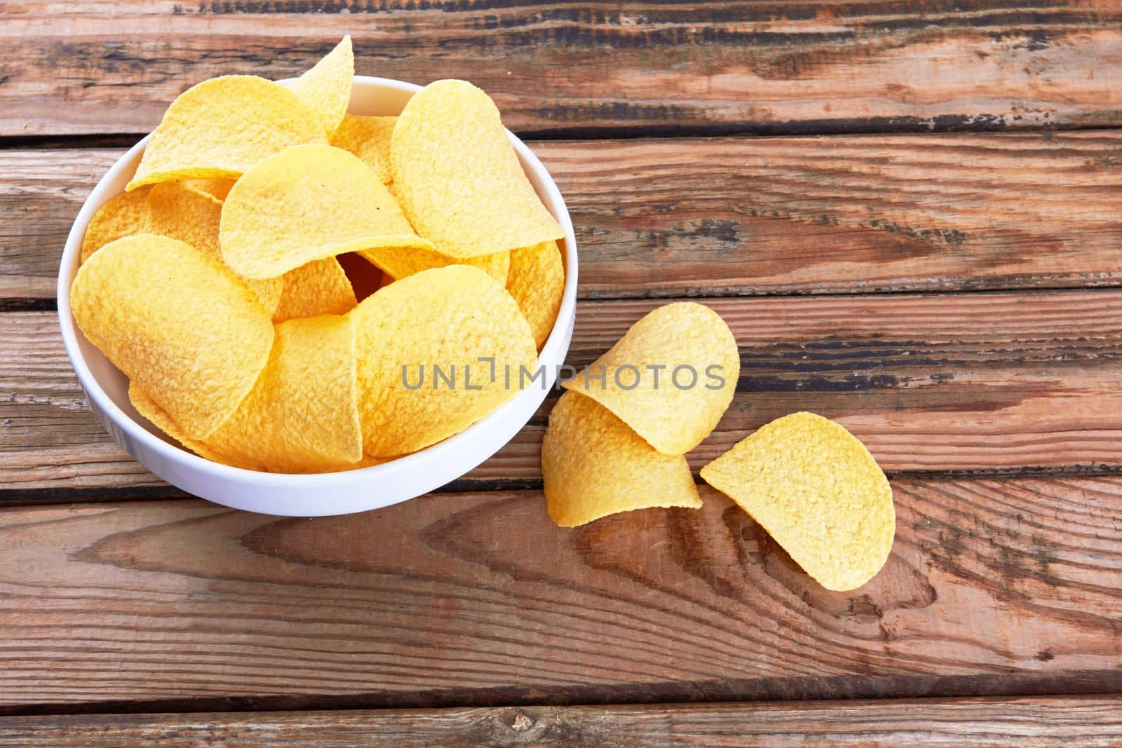 Potato chips on a wooden surface in a saucer