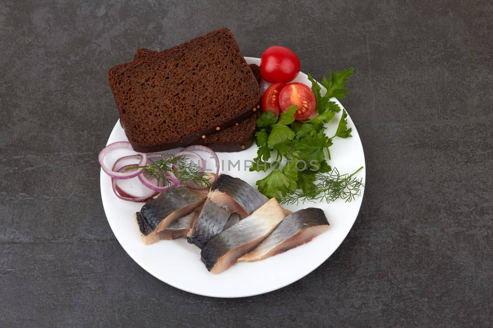 Slices of herring fish on stone black surface