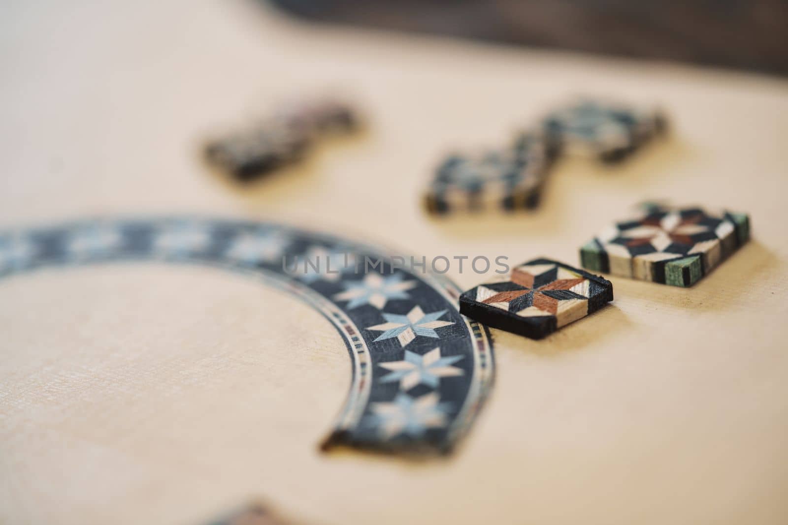 Closeup soft focus of wooden blocks with authentic ornaments of typical taracea of Granada, placed on Spanish flamenco guitar blank in luthier workshop