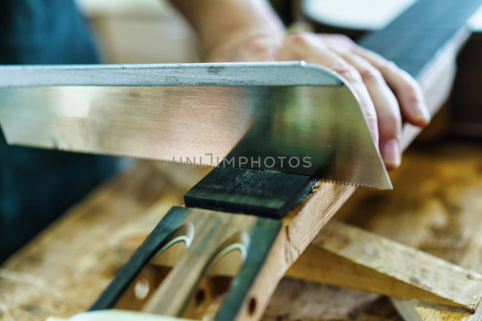 Spanish guitar maker, or luthier, working on a flamenco guitar. Unrecognizable craftsman marking the frets on the neck of a flamenco guitar, as part of the handcrafted manufacturing process.