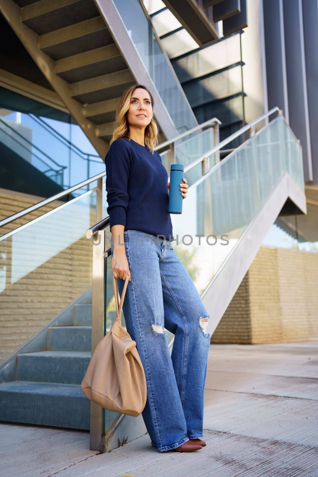 Stylish woman with bag and thermos near steps by javiindy