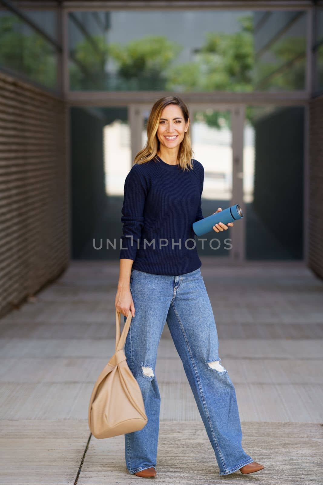 Middle-aged woman carrying a bag and an eco-friendly ecological metal thermos for coffee. by javiindy