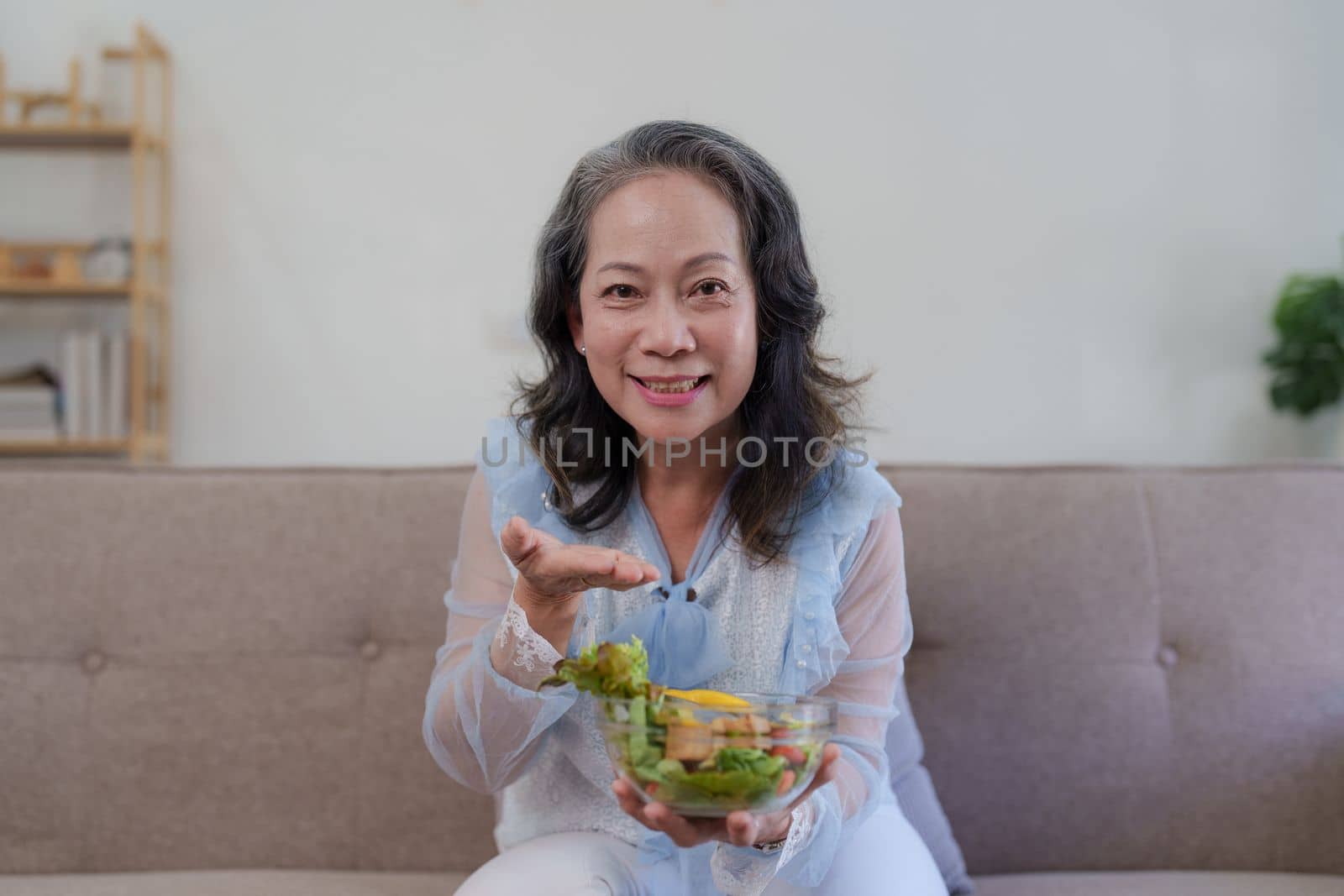 Happy old asian woman eating fresh green salad. Senior woman good healthy at home. Exercise and healthy diet concept.