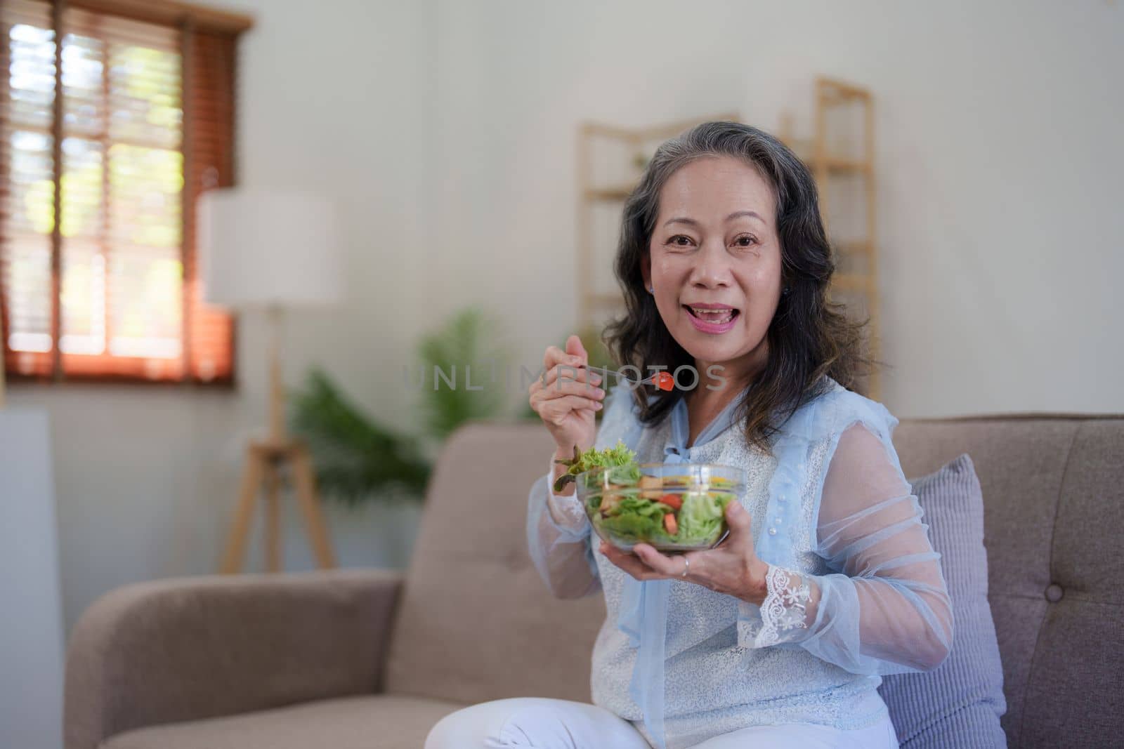 Happy old asian woman eating fresh green salad. Senior woman good healthy at home. Exercise and healthy diet concept.