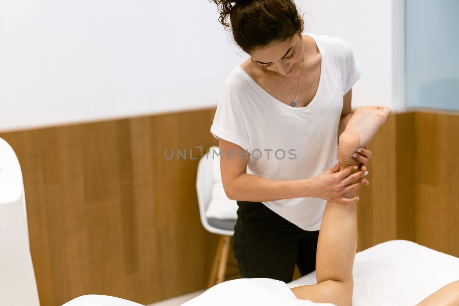 Middle-aged woman having a leg massage in a beauty salon. Body care treatment in a beauty centre.