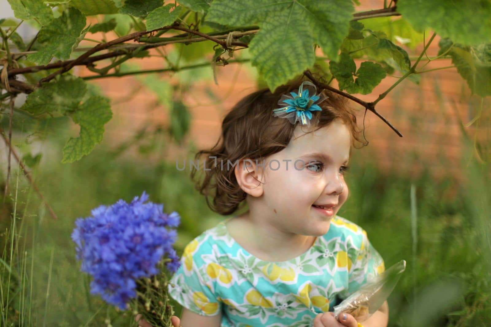 Cute little girl in autumn park holding bunch of yellow leaves. High quality photo