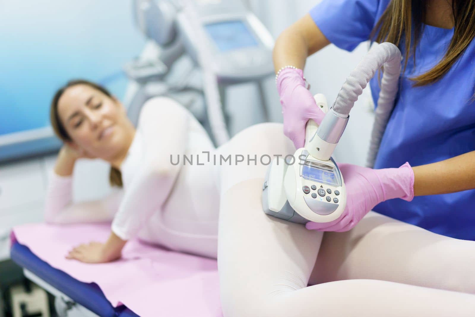 Middle-aged woman in special white suit having a anti cellulite massage with spa apparatus