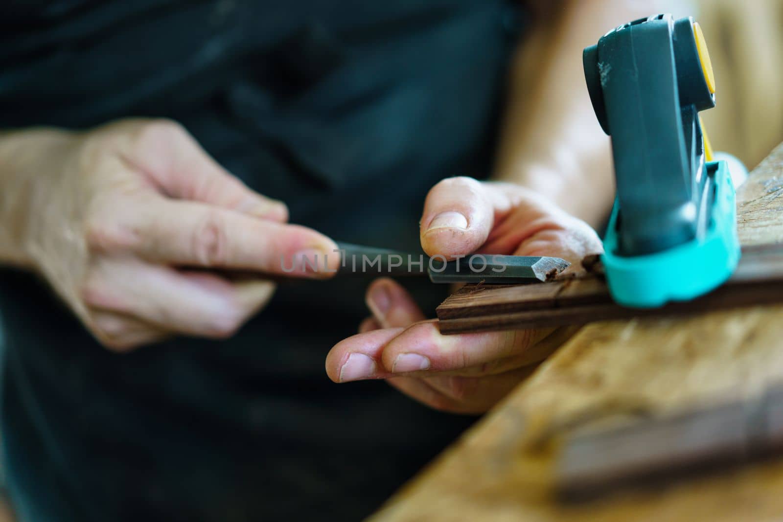 Soft focus of unrecognizable craftsman carving part for Spanish flamenco guitar on workbench during work in luthier workshop
