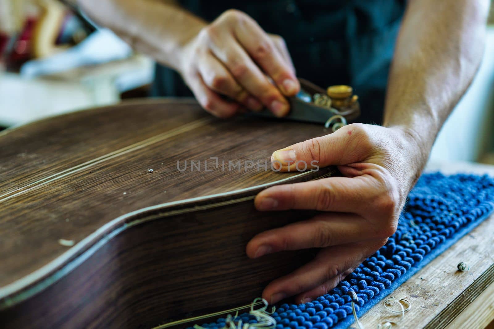 Soft focus of unrecognizable craftsman carving part for Spanish flamenco guitar on workbench during work in luthier workshop