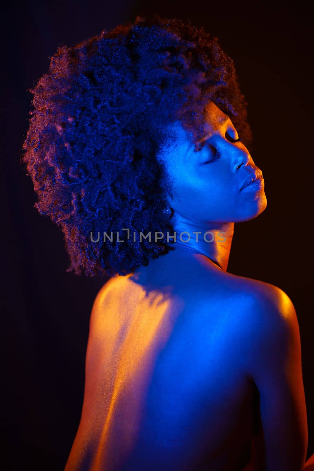 Naked African American model under neon illumination by javiindy