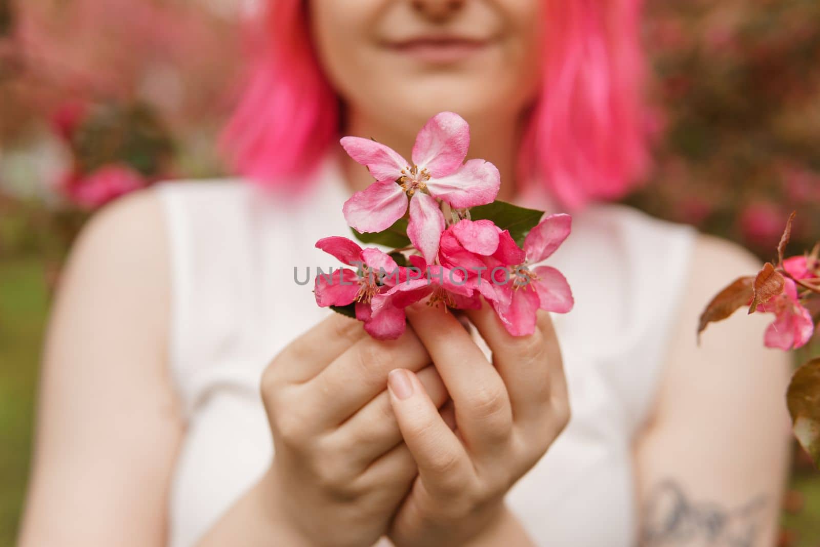 Blooming pink Apple. Apple trees bloom. Young girl with pink hair in Apple orchard. Selective focus.