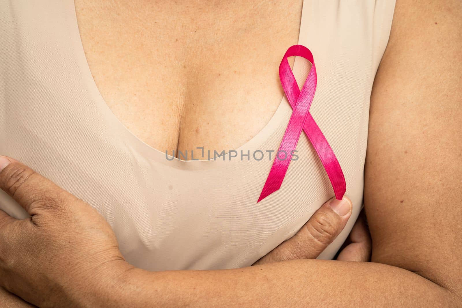 Breast cancer, pink ribbon at Asian senior lady for supporting awareness, symbol of World Breast Cancer Day. by pamai