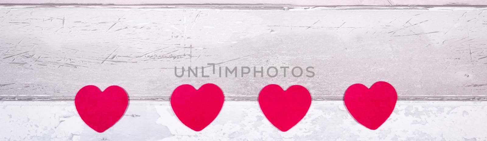 Red felt hearts on a background of old wooden planks resembling an old parquet floor. Concept of valentines day and love in general.