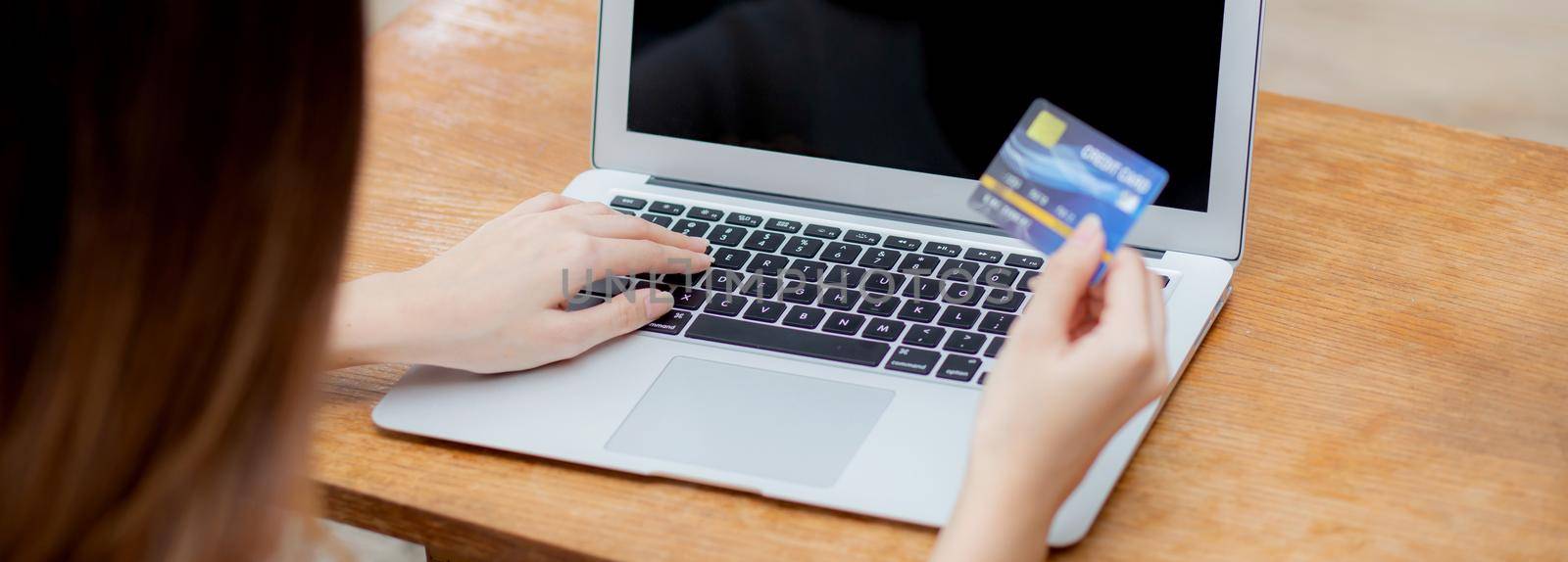 Young asian woman using laptop computer display blank screen shopping online with credit card on table at home, girl purchase and payment with debit card, e-commerce and technology, lifestyle concept.