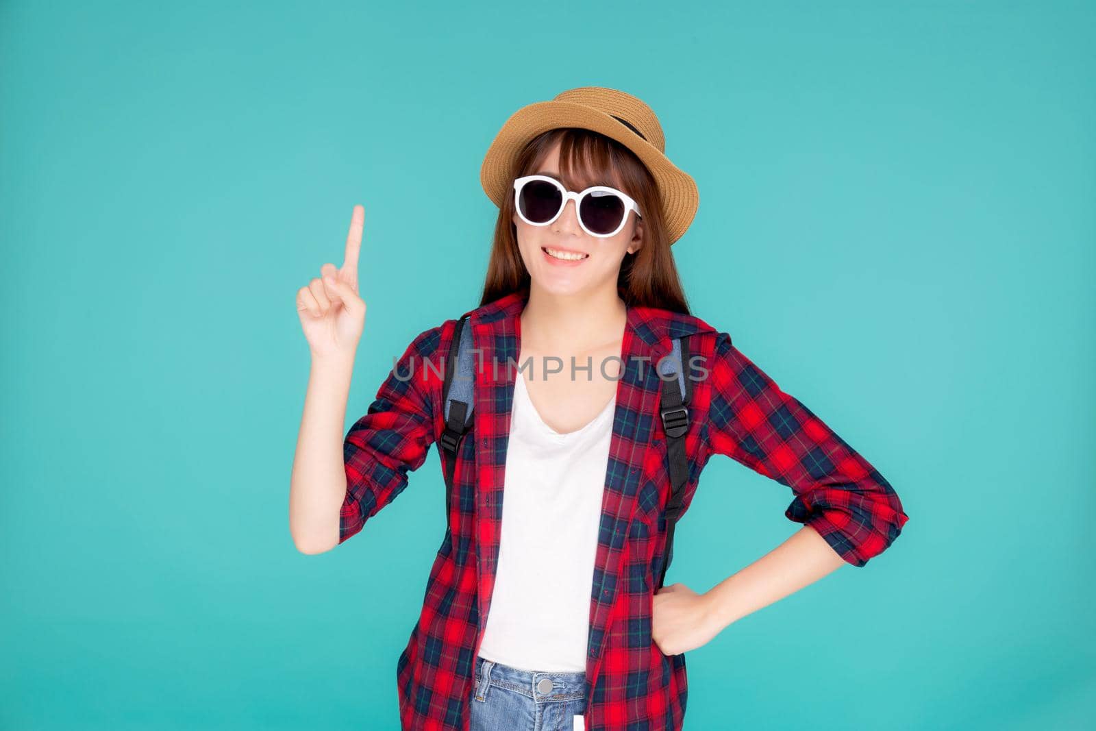 Beautiful portrait young asian woman wear sunglasses and hat smile and enjoy in summer gesture presenting and pointing something isolated on blue background, tourist girl in vacation travel concept. by nnudoo