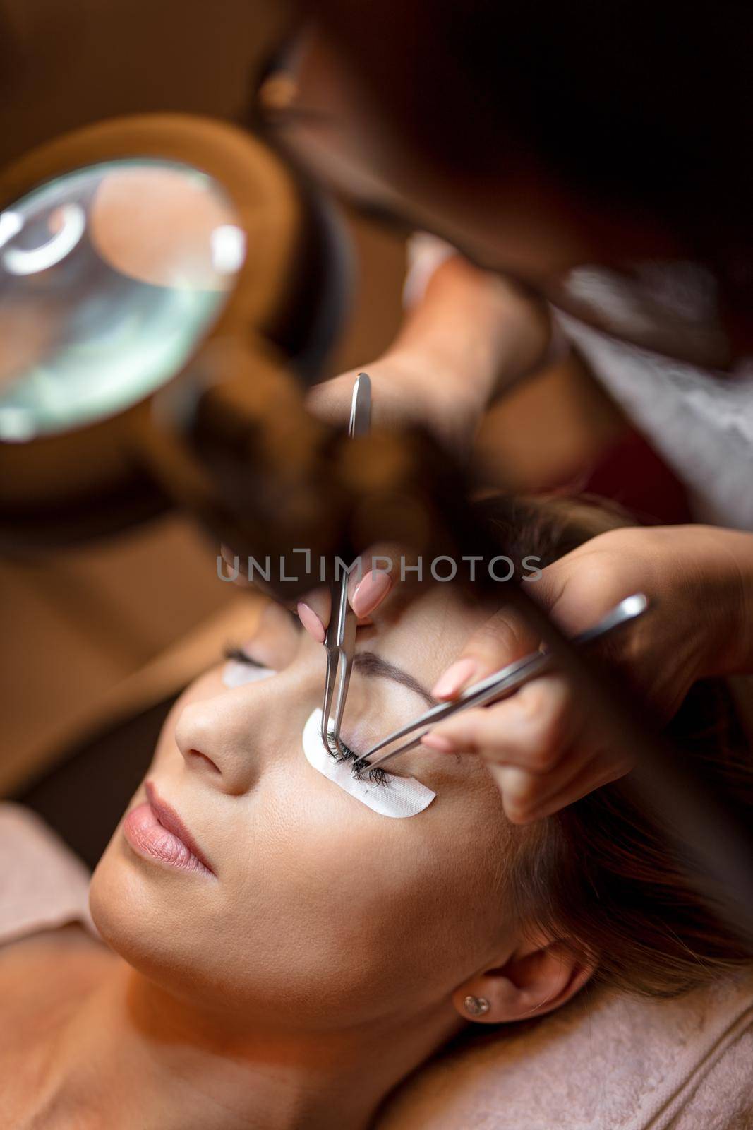 Beautician applying extended eyelashes to model.Close-up.