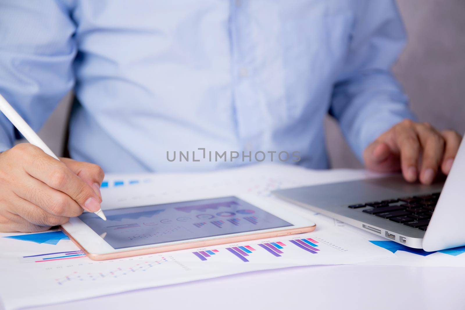 Businessman planning about graph and chart of investment with report for finance on tablet computer on desk, statistic for financial and profit with document, digital marketing, business concept.