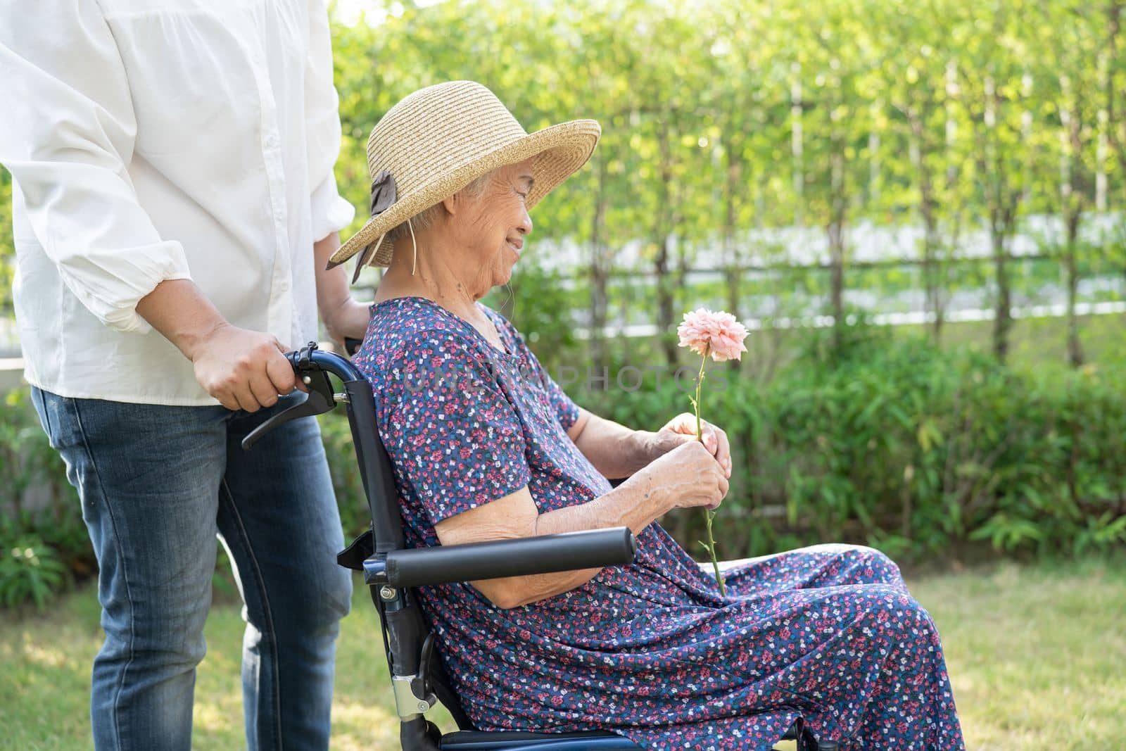 Caregiver help and care Asian senior or elderly old lady woman patient sitting and happy on wheelchair in park, healthy strong medical concept. by pamai