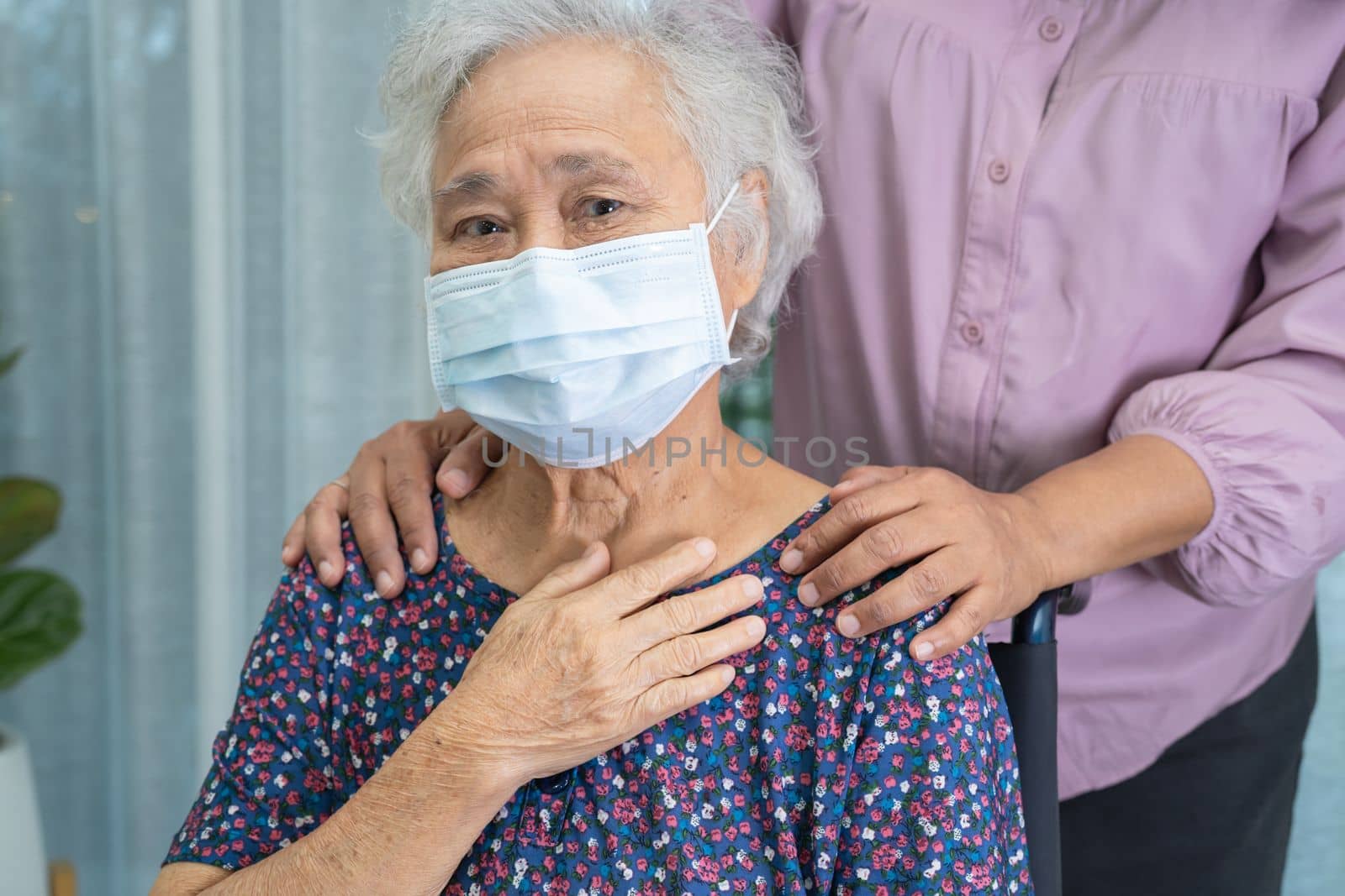 Caregiver help Asian senior or elderly old lady woman sitting on wheelchair and wearing a face mask for protect safety infection Covid19 Coronavirus. by pamai