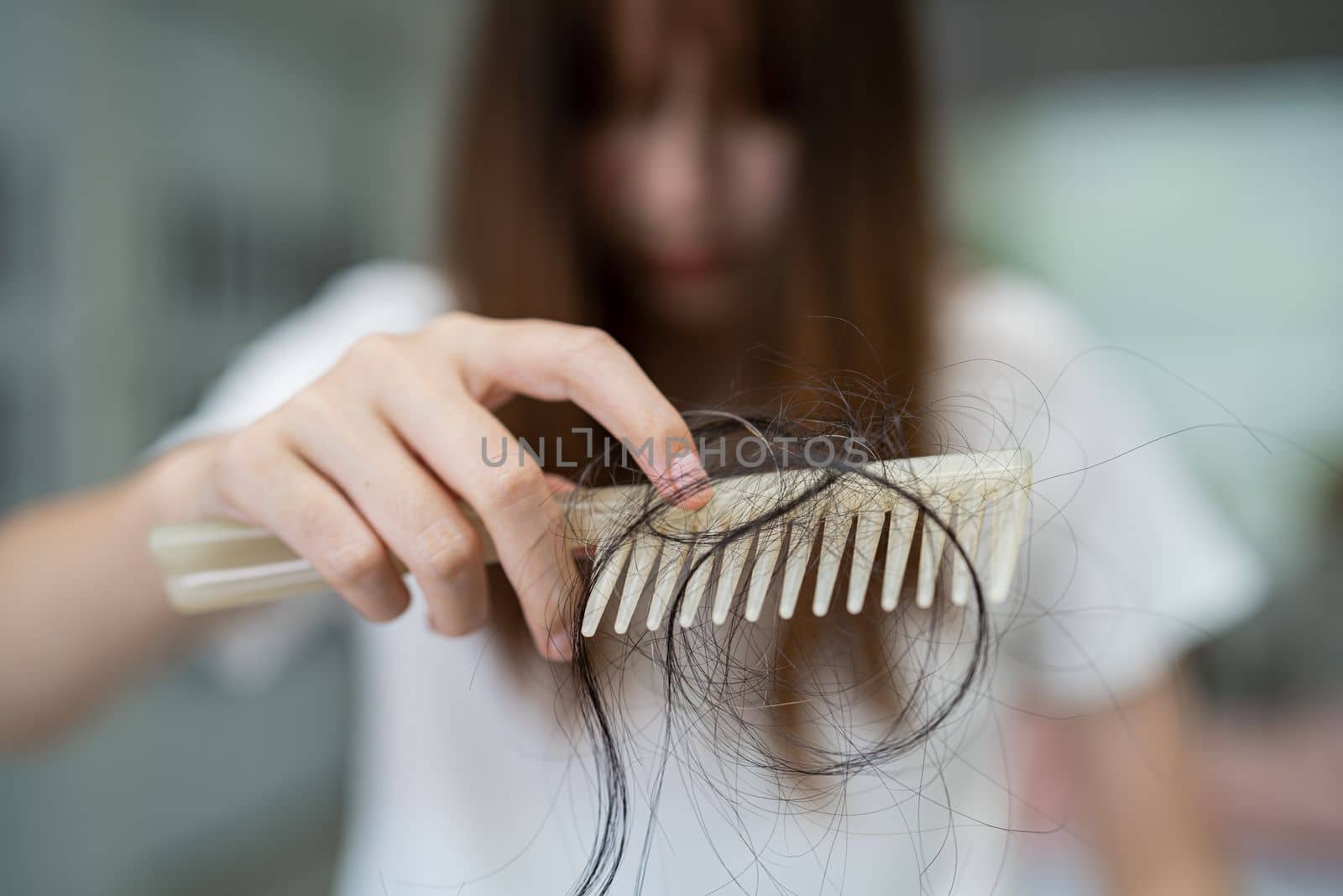 Asian woman have problem with long hair loss attach to comb brush. by pamai