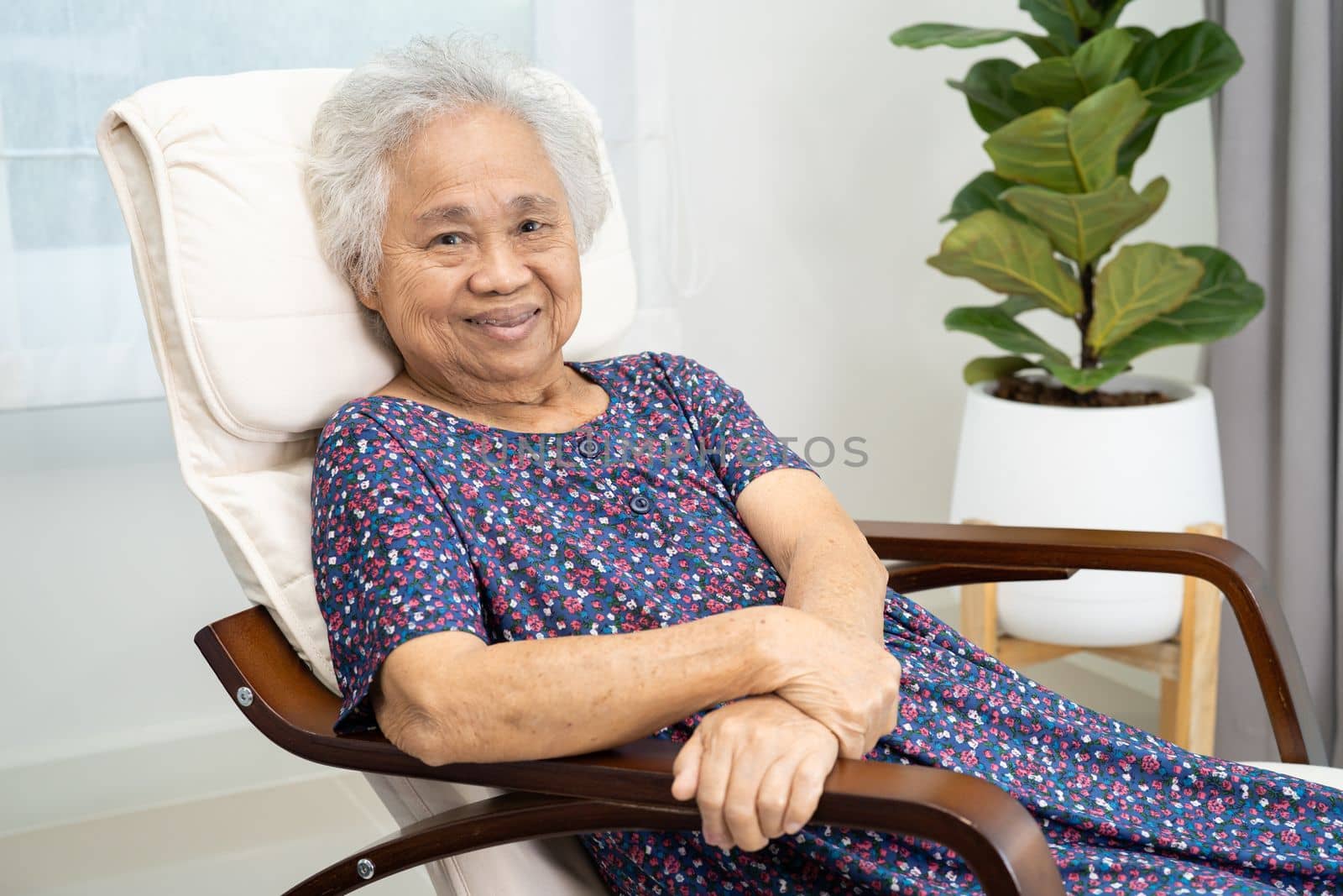 Asian elderly woman sitting and relaxing with happy in rocking chair at room in home.