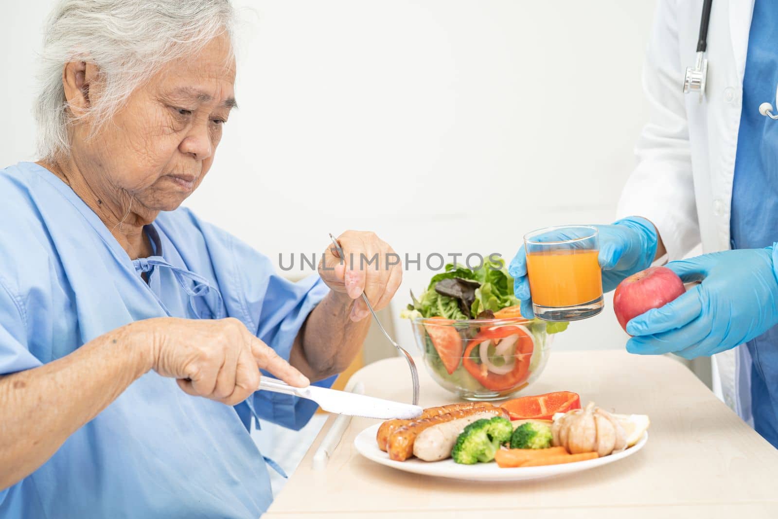 Asian senior or elderly old lady woman patient eating breakfast and vegetable healthy food with hope and happy while sitting and hungry on bed in hospital. by pamai