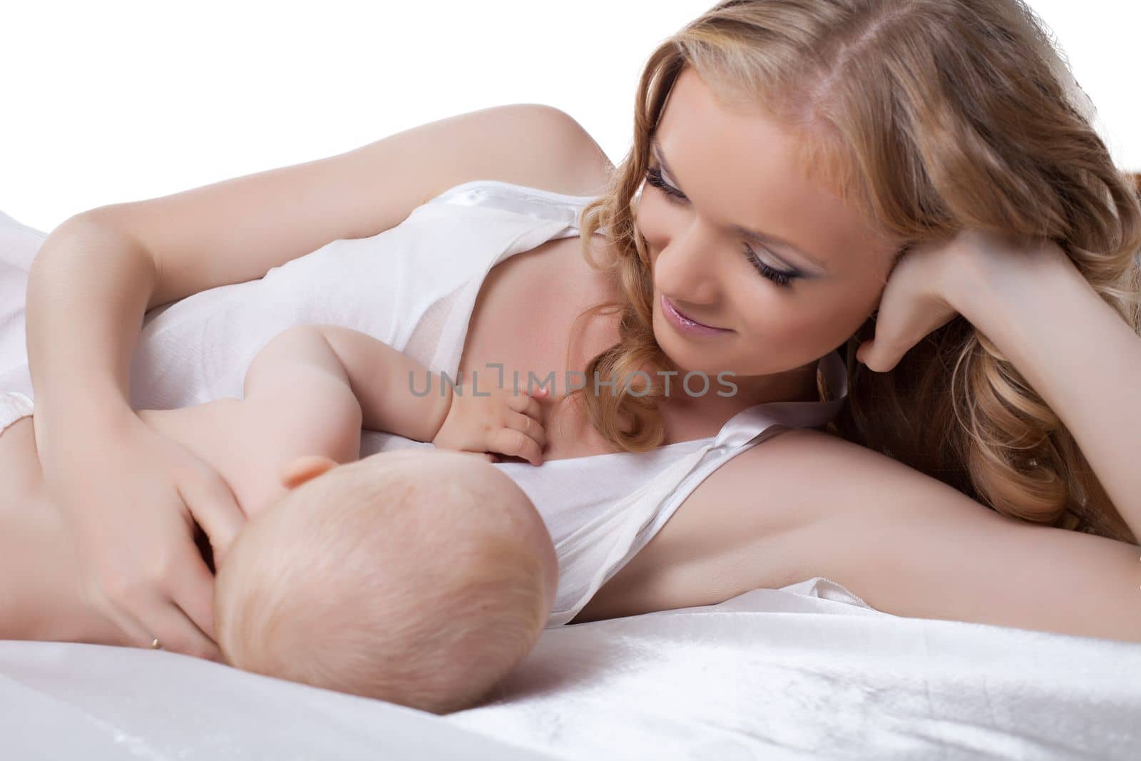 Mother with baby in bed. Isolated on white