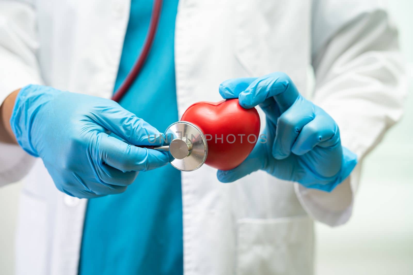 Doctor holding a red heart in hospital ward, healthy strong medical concept.