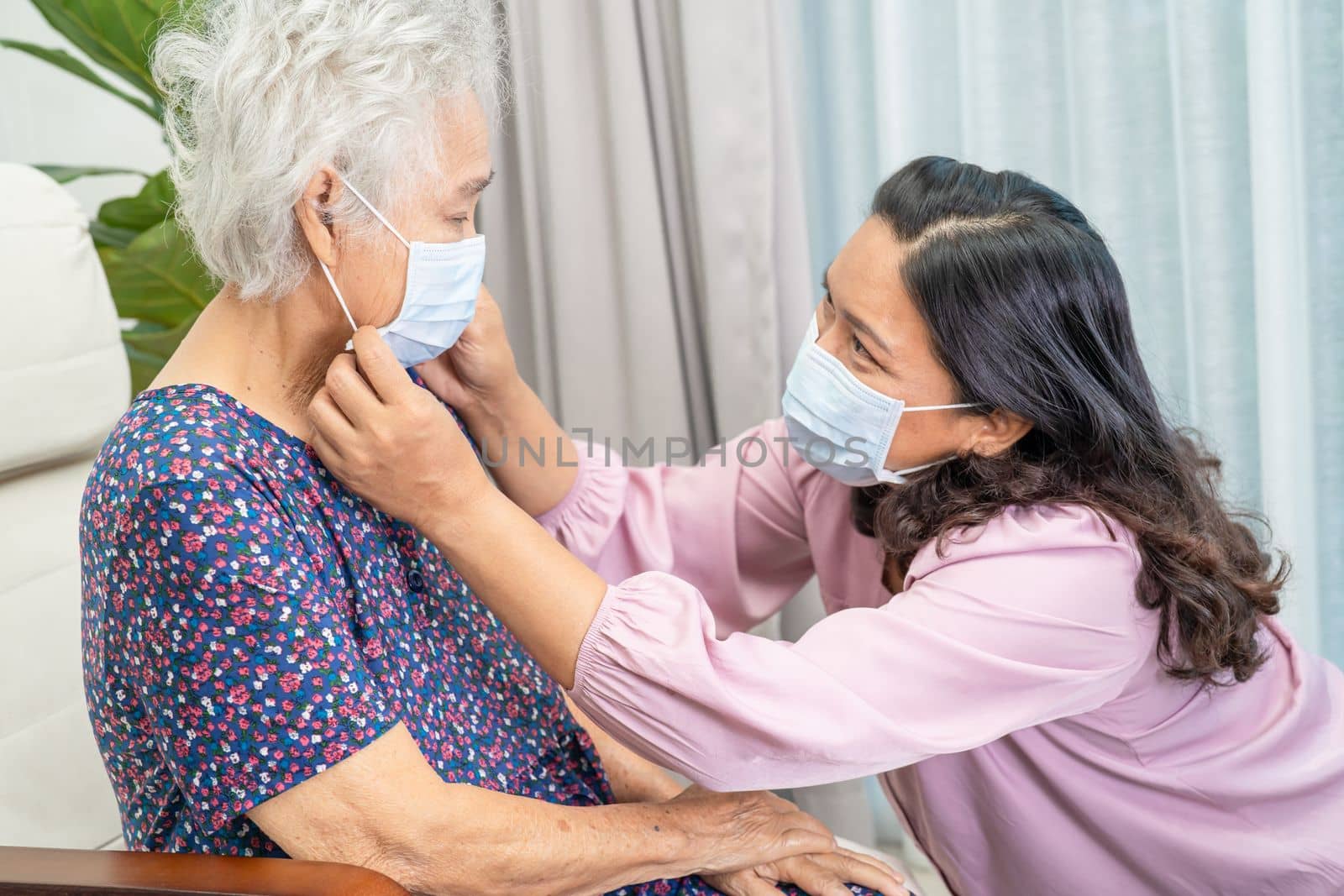Caregiver help and talk with Asian senior or elderly old lady woman wearing a face mask for protect safety infection Covid19 Coronavirus in park.