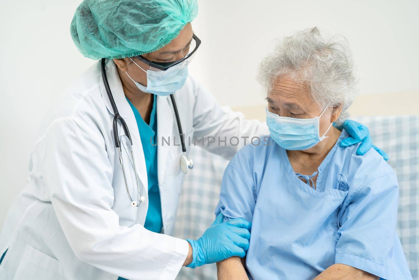Doctor help Asian senior or elderly old lady woman patient wearing a face mask in hospital for protect safety infection and kill Covid19 Coronavirus.