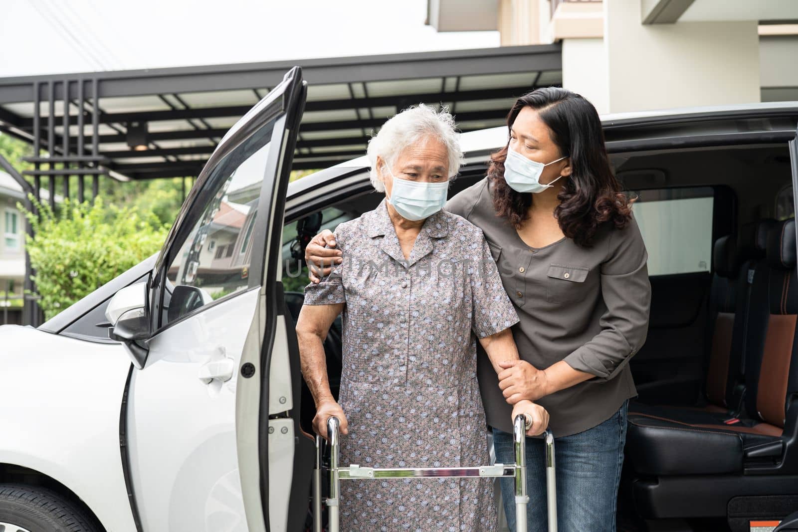 Help and support asian senior or elderly old lady woman patient walk with walker prepare get to her car, healthy strong medical concept. by pamai