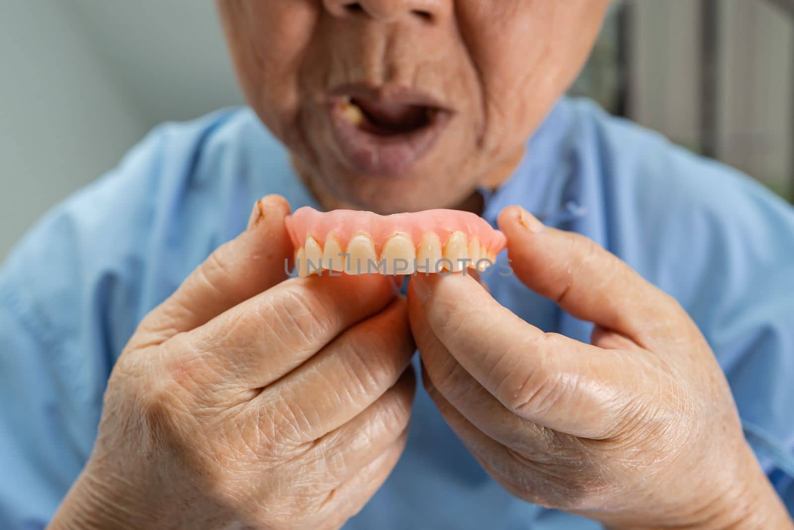 Asian senior or elderly old woman patient holding to use denture in nursing hospital ward, healthy strong medical concept by pamai