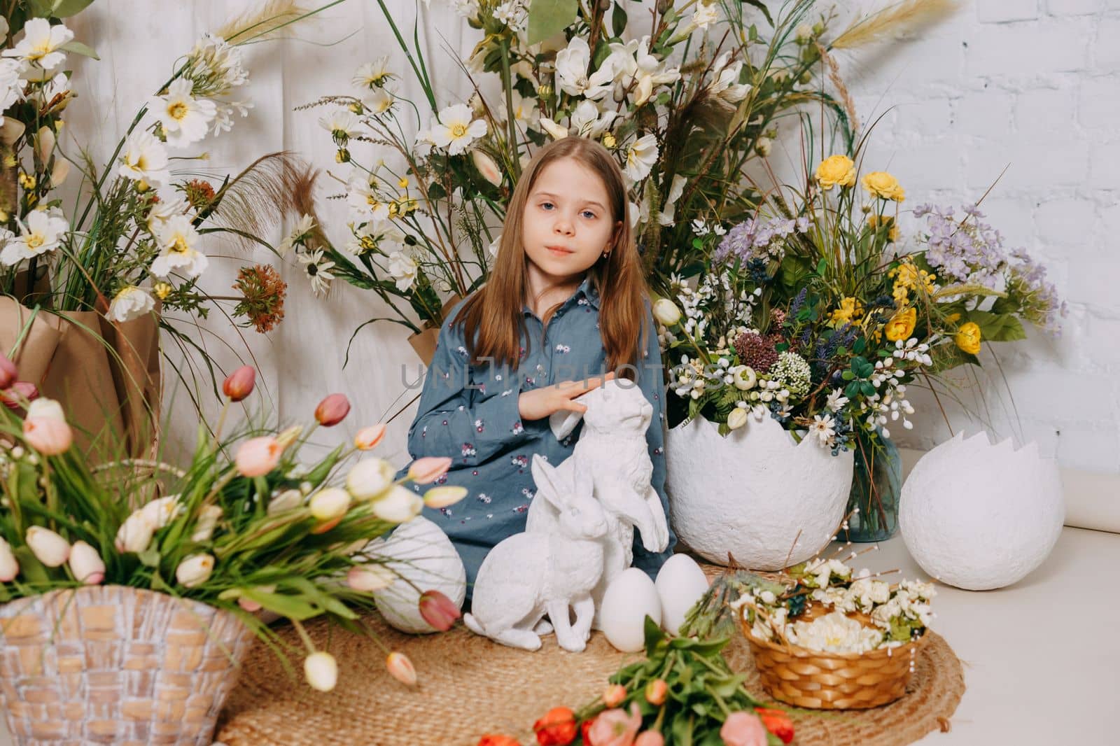 Two girls in a beautiful Easter photo zone with flowers, eggs, chickens and Easter bunnies. Happy Easter holiday