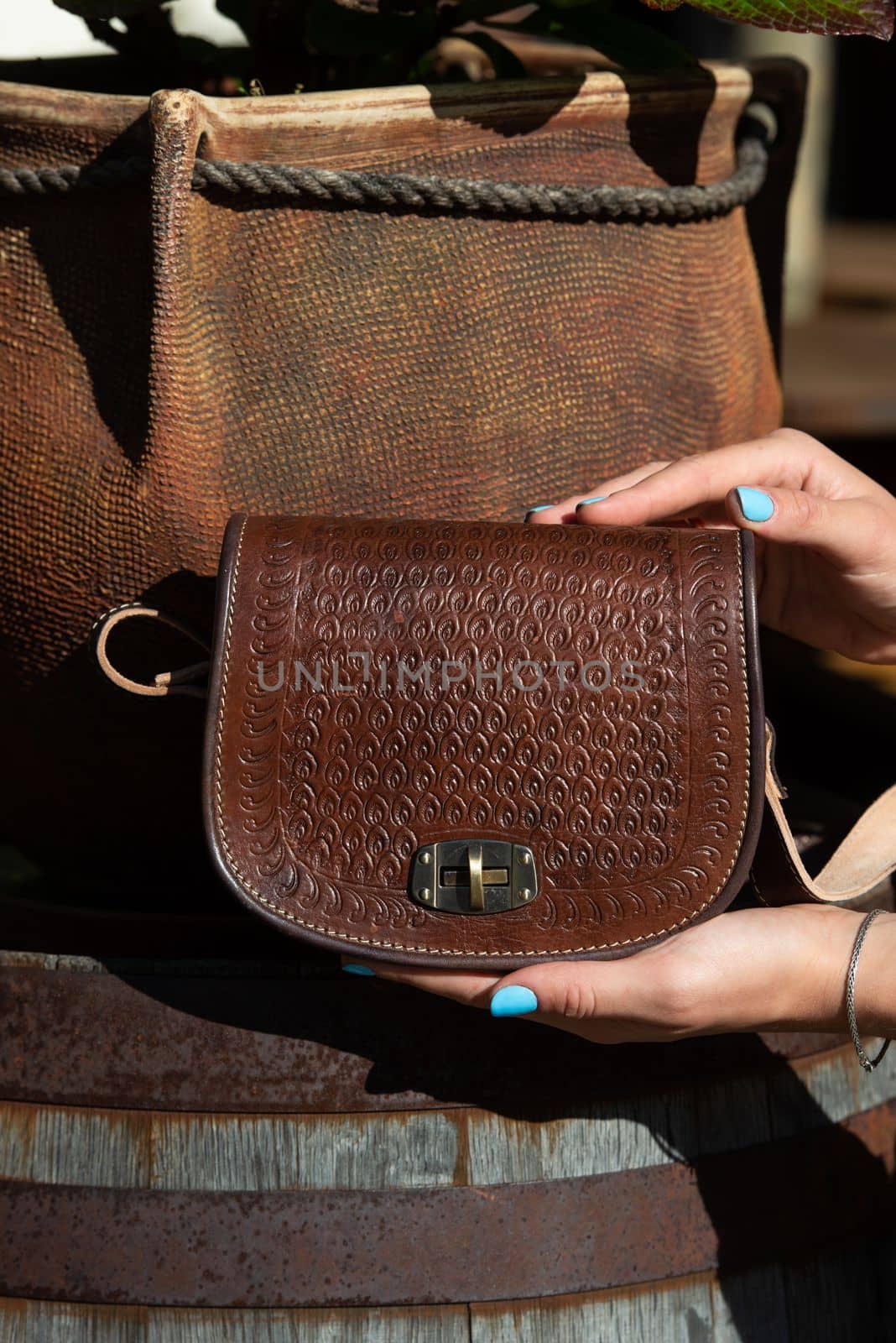 small brown women's leather bag with a carved pattern. street photo