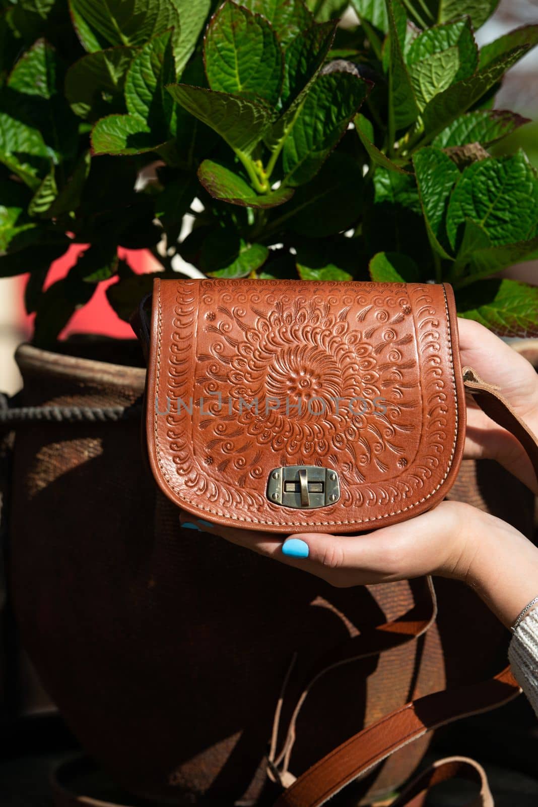 small brown women's leather bag with a carved pattern. street photo. selective focus