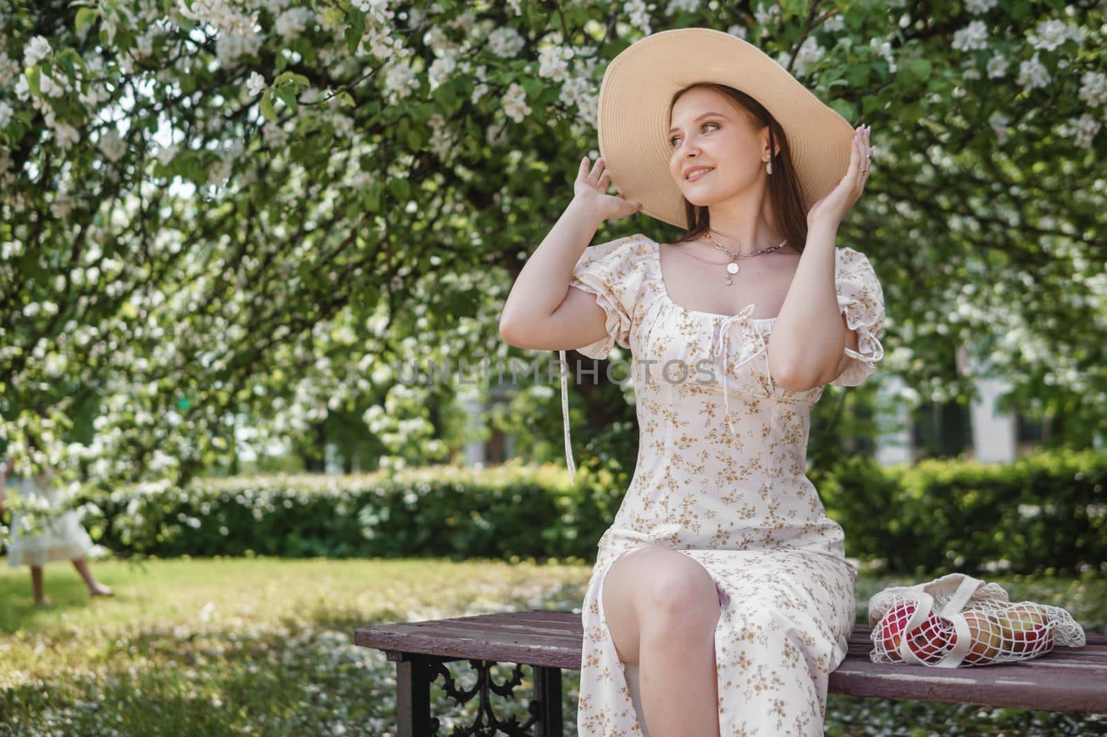 An attractive long-haired woman walks in the spring in the park of blooming apple trees. Spring portrait of a woman