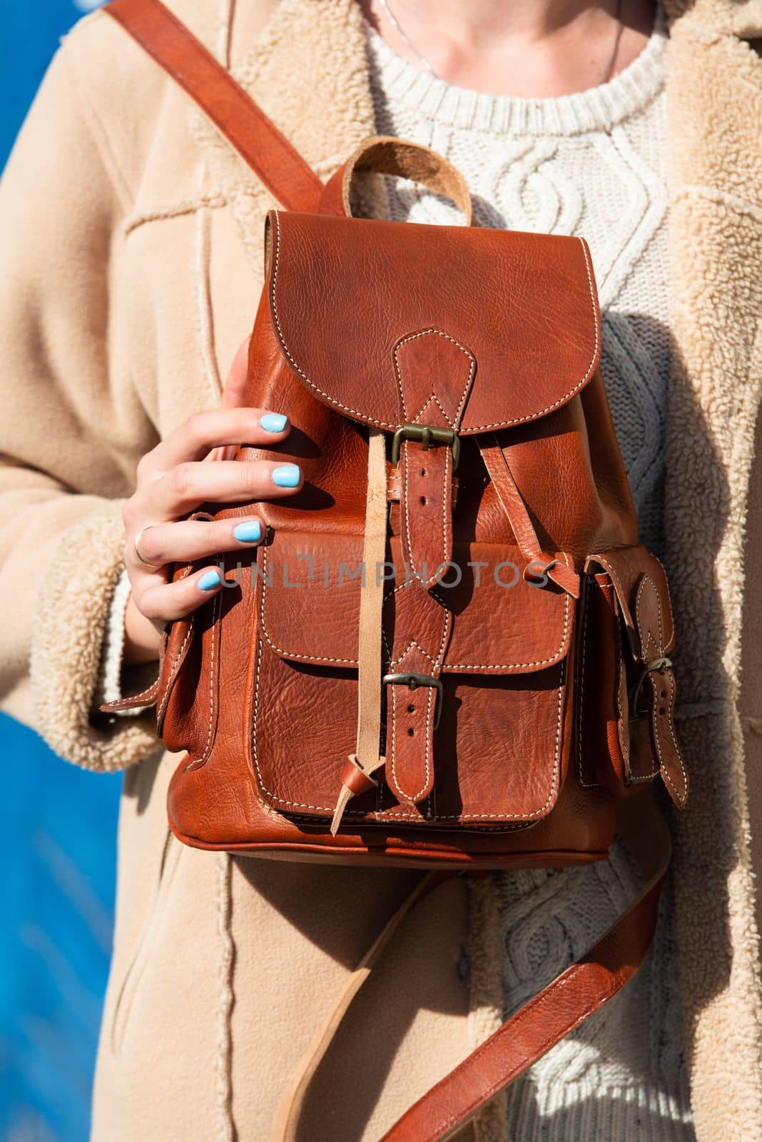 Part photo of a blond woman with a light brown leather backpack with antique and retro look. Outdoors photo by Ashtray25