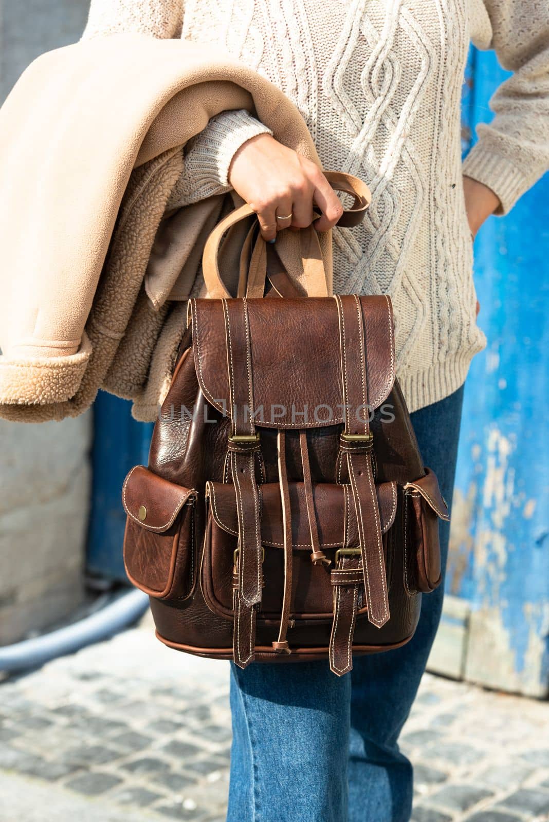 Woman with a brown leather backpack with antique and retro look. Outdoors photo.