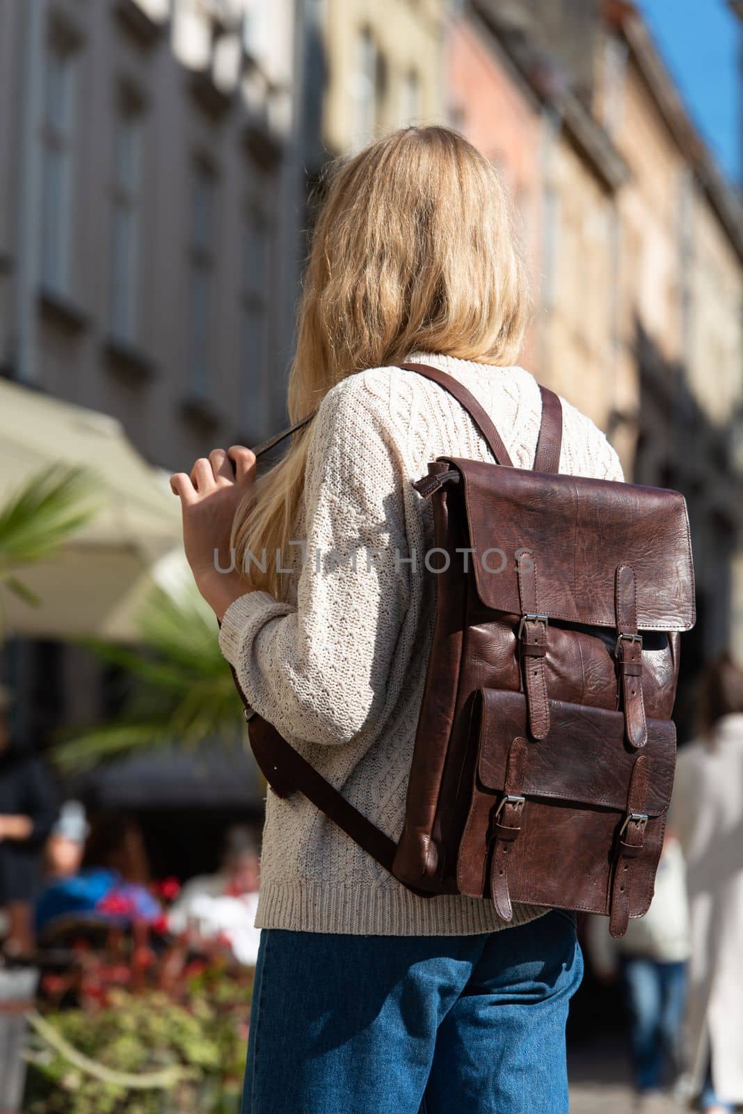 Part photo of a woman with a brown leather backpack with antique and retro look. Outdoors photo by Ashtray25