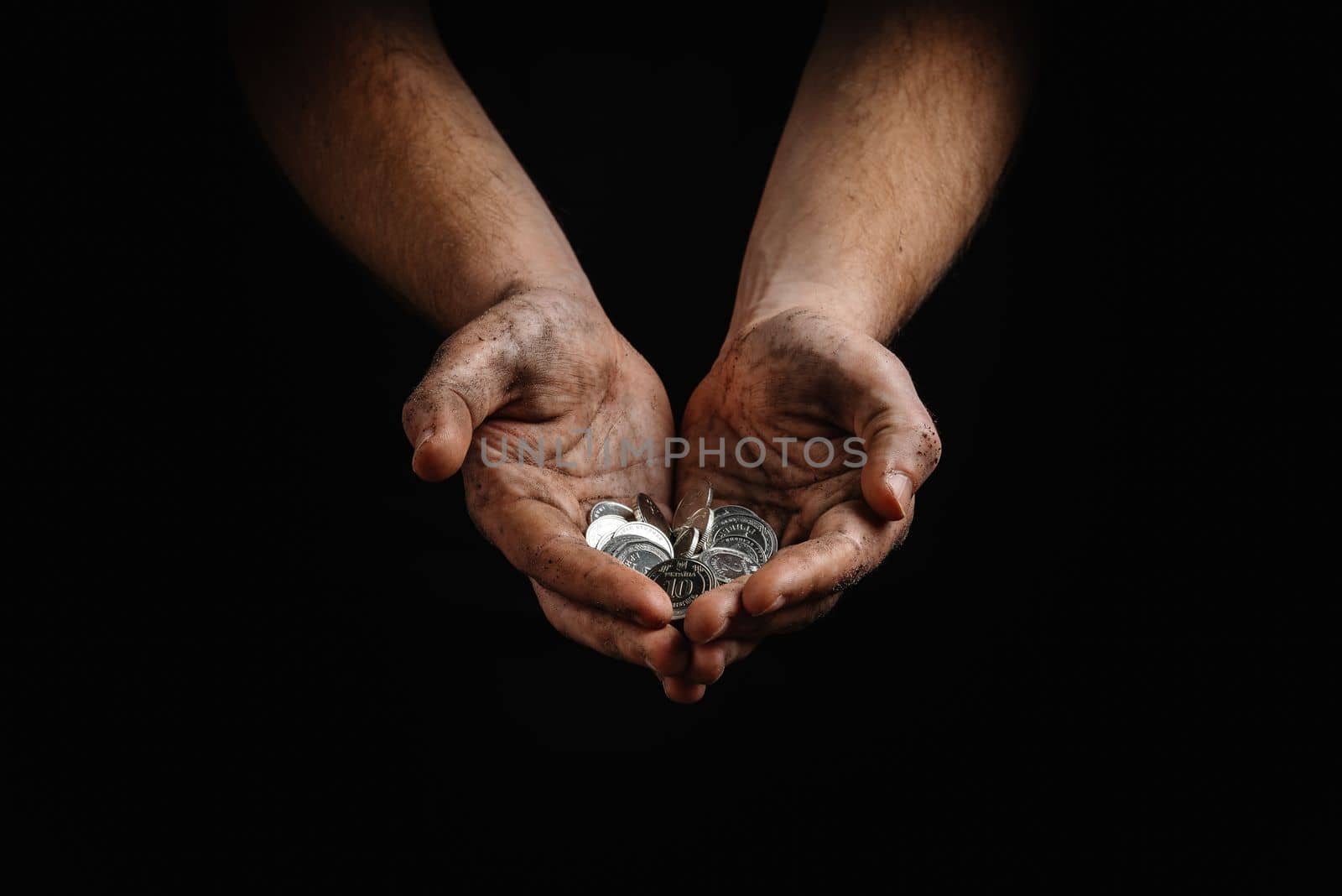 poverty in Ukraine. Dirty hands of a poor homeless man holding Ukrainian hryvnias in coins.