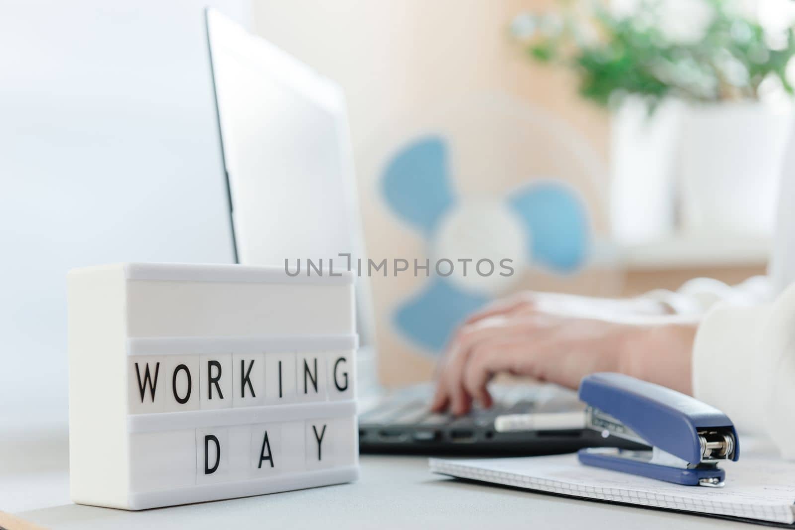 Workplace with a laptop, hands of a man, notepad on a white background. Freelancer's workplace. Workday text inscription and blank space for text.