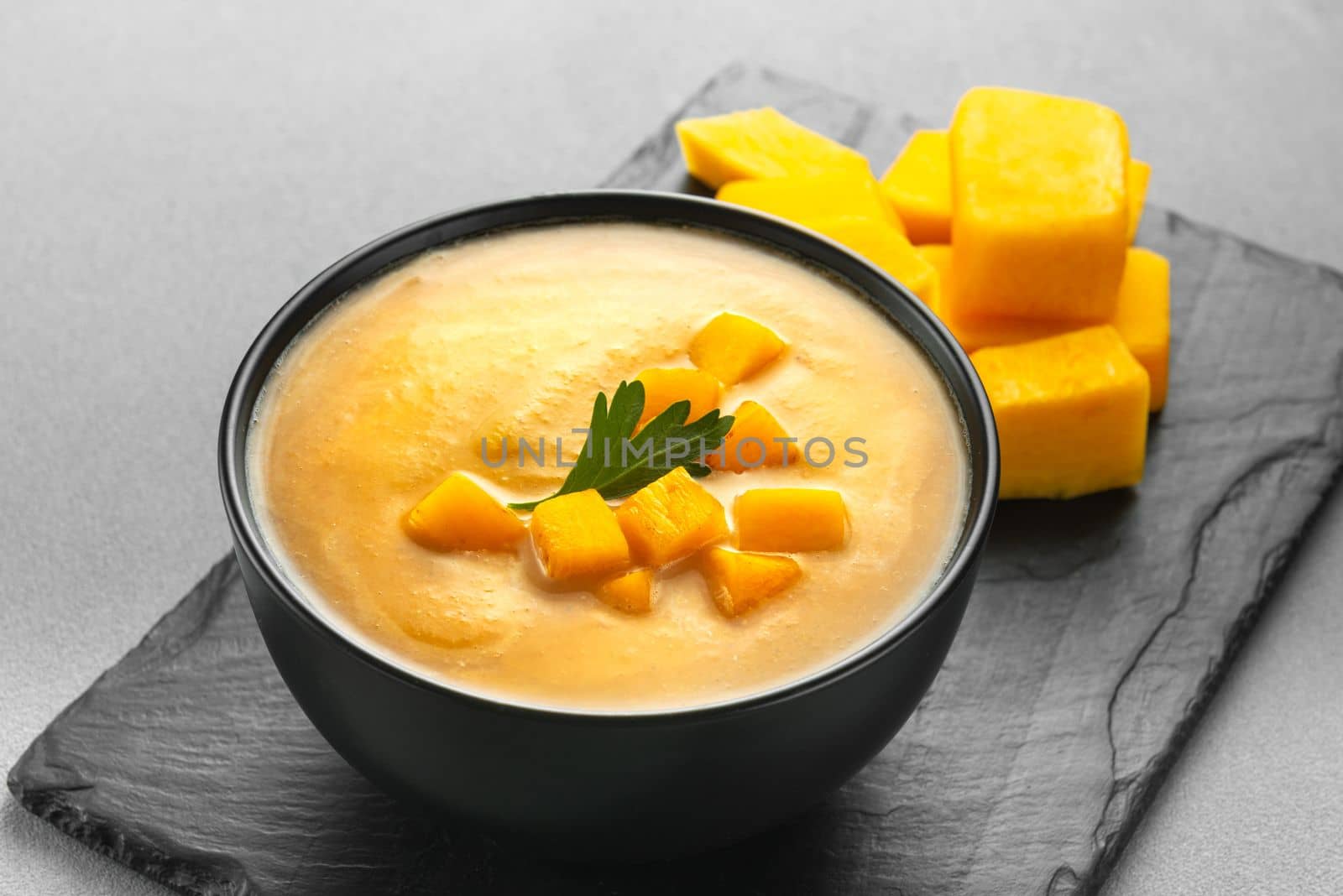 pumpkin cream soup mashed potatoes on a gray background. Vegan curried pumpkin lentil soup puree in a bowl. Space for text. Pescatarian Eating, Flexitarian Eating, Reducetarian Eating