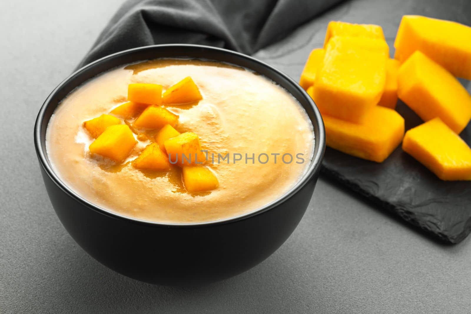 Vegetarian fall pumpkin puree soup in a black bowl . Pumpkin Soup.