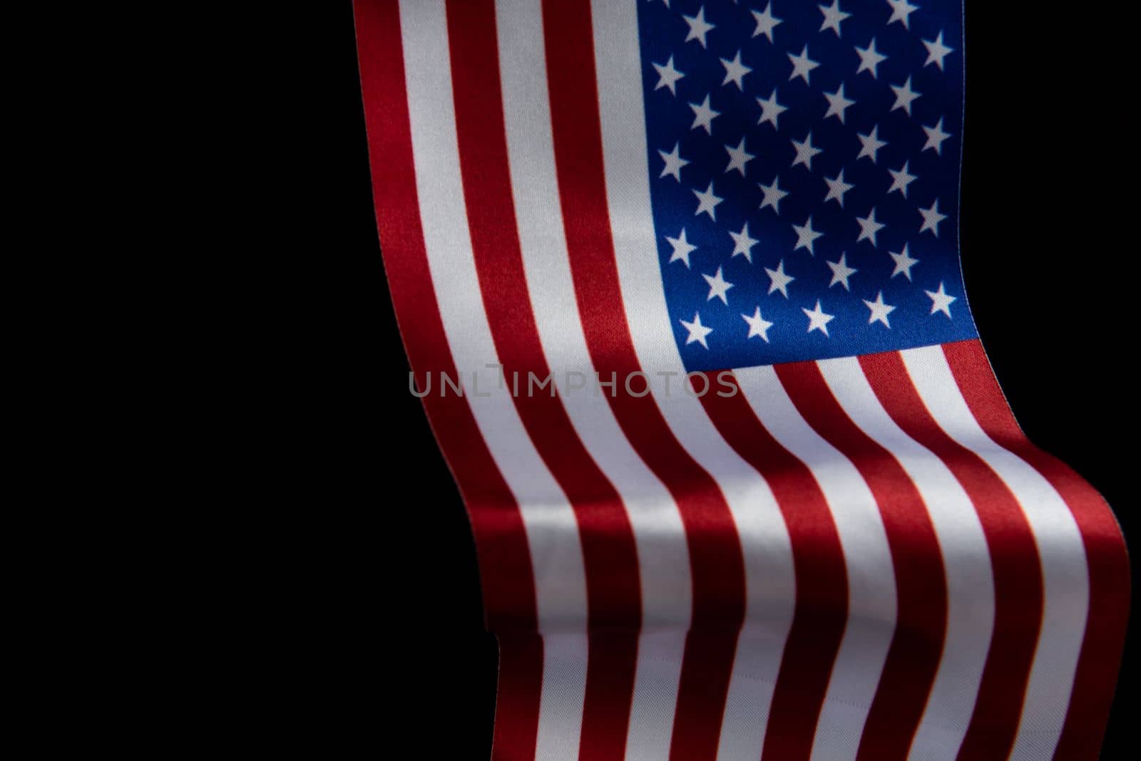 The U.S. flag is developing in the wind against a dark background. Isolate.